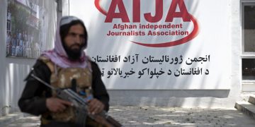 An armed Taliban member stands guard outside the Afghan Independent Journalists Association (AIJA) office in Kabul, symbolizing the increasing restrictions on press freedom and independent media in Afghanistan. (Photo Credit: Wakil KOHSAR / AFP)