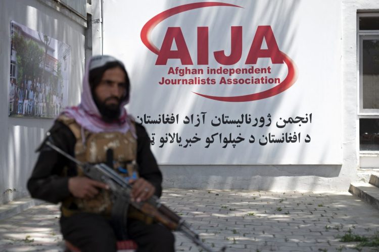 An armed Taliban member stands guard outside the Afghan Independent Journalists Association (AIJA) office in Kabul, symbolizing the increasing restrictions on press freedom and independent media in Afghanistan. (Photo Credit: Wakil KOHSAR / AFP)
