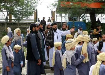 Taliban officials stand with children wearing traditional attire at what appears to be a state-run facility in Afghanistan, amid concerns about the closure of private orphanages and transfer of children to government control. (Photo Credit: MEW_GOV_AF)