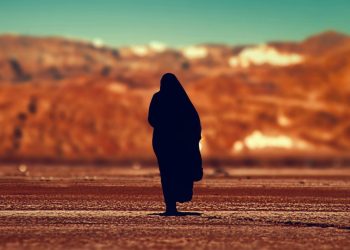 A lone woman stands against a barren landscape, reflecting the silence, fear, and forced complicity imposed on women under Taliban rule. (Photo Credit: WFWP)