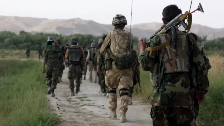 Afghan special forces soldiers patrol in formation through rural terrain. These elite units, known as the "Triples," were trained by and fought alongside British forces before being largely denied resettlement in the UK following the Taliban takeover. Photo Credit: Getty Images