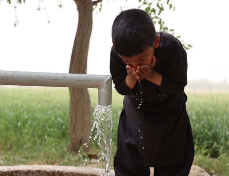 A child drinks water from a pipe in rural Afghanistan amid severe water shortages affecting millions across the country. (Photo Credit: OCHA)