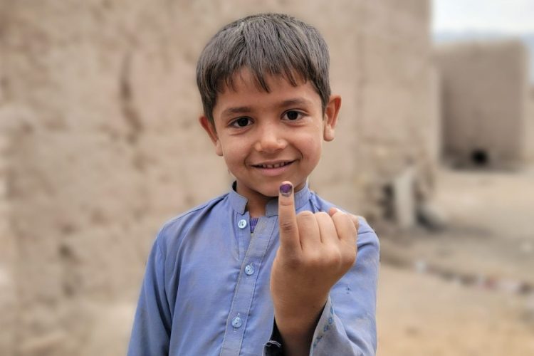 A young boy in Afghanistan proudly displays his marked finger after receiving the polio vaccine, a simple yet powerful protection against a paralyzing disease that continues to threaten children's futures in the region. (Photo Credit: Polio Free Afghanistan)