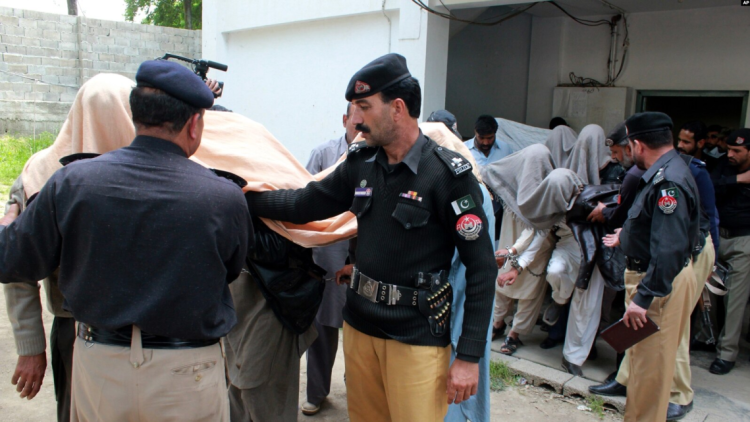 akistani police escort handcuffed detainees during an operation, amid a sweeping crackdown targeting refugees from Afghanistan across multiple cities in Pakistan. (Photo Credit: AP)