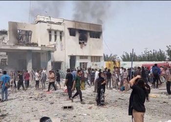 Devastation in Mahallat after reported attack, with smoke rising from damaged buildings and locals gathered at the scene. (Photo Credit: X/@Seyed Abbas Araghchi)