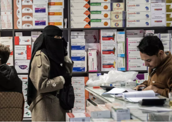 Three people inside a pharmacy in Herat amid rising medicine prices. Photo Credit: AFP