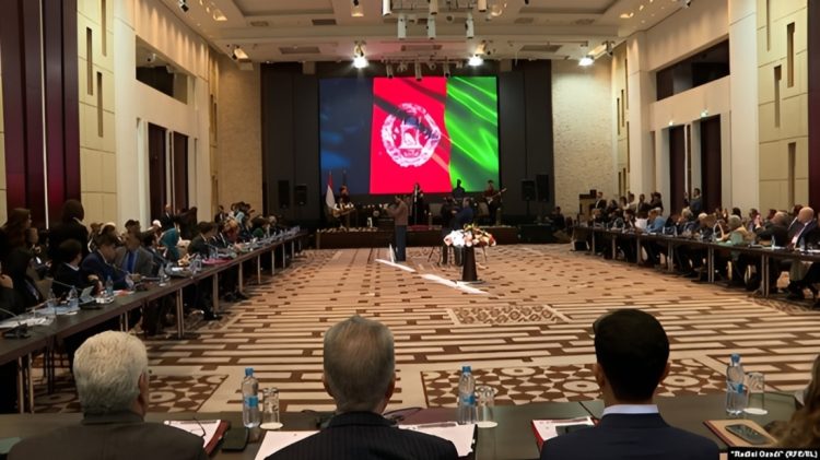 Afghan opposition conference hall with long tables, delegates, and large screen showing Taliban flag, addressing unity challenges. (Photo Credit: Radio Azadi / RFE/RL)