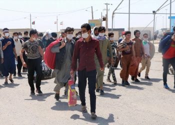 Afghanistan asylum seekers walk near a border area carrying belongings amid uncertainty and displacement. (Photo Credit: DW)