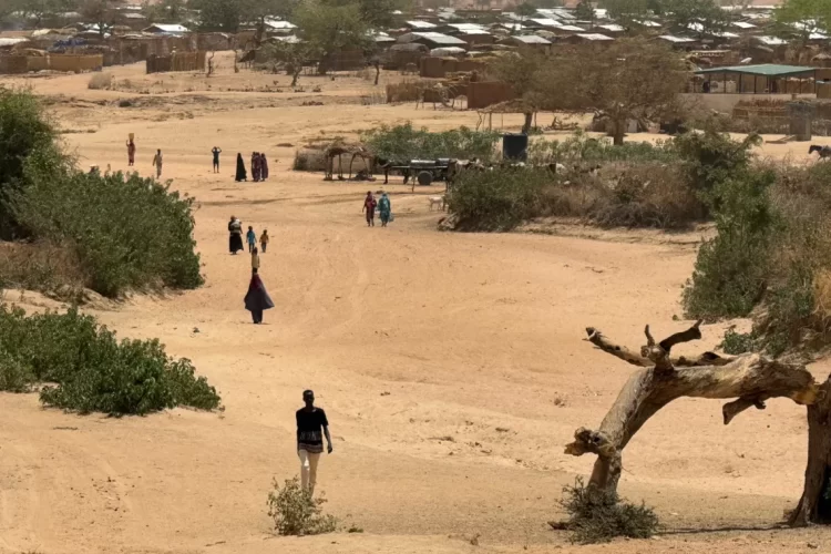 A view of a dry, sandy settlement in eastern Chad where residents walk across arid terrain amid resource scarcity. (Photo Credit: AP)
