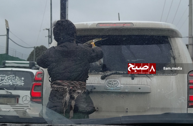 A child cleans the rear window of a Toyota SUV during a traffic jam on a Kabul street in cold, rainy weather. (Photo Credit: 8am.media)