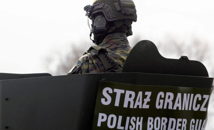 Polish soldier standing in uniform during deportation-related operation context. (Photo Credit: OK.PRESS)