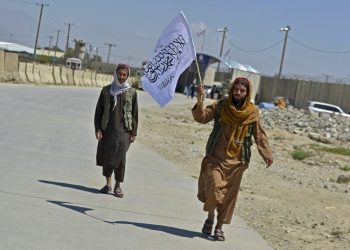 Taliban fighters wave flag over seized land (Photo Credit: Ahmad SAHEL ARMAN / AFP)