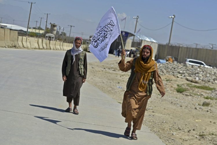 Taliban fighters wave flag over seized land (Photo Credit: Ahmad SAHEL ARMAN / AFP)