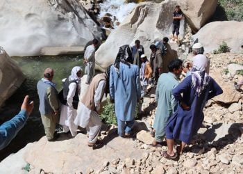 A crowd of people gathered near the water in Daikundi province following a drowning incident, as locals observed the scene while search efforts continued. (Photo credit: RTA Daikondi)
