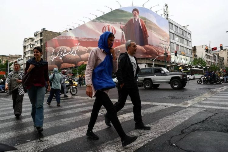 A crowded street in Iran is seen with a backdrop board displaying Iran’s Supreme Leader amid ongoing nationwide internet disruptions. (Photo credit: REUTERS)
