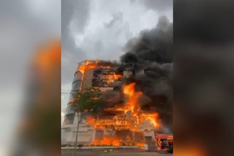 A large fire engulfs a shopping center building in Andisheh near Tehran, sending thick smoke into the sky as emergency crews respond. (Photo credit: aljazeera)