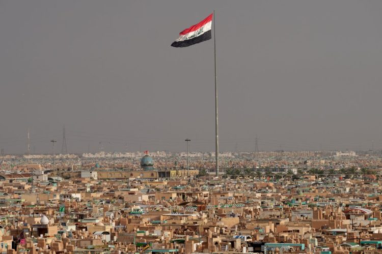 The Iraqi flag flies over a densely populated urban landscape, as Iran's Revolutionary Guard announces strikes against armed groups in the country's north. (Photo credit: QASSEM AL-KAABI / AFP)