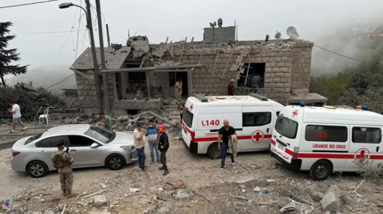 Lebanese Red Cross ambulances and residents gather at the site of a destroyed home following an Israeli airstrike in southern Lebanon. (Photo credit: Reuters)