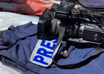 A Panasonic professional video camera rests on a blue press vest marked "PRES" during a media assignment. (Photo credit: Reuters)