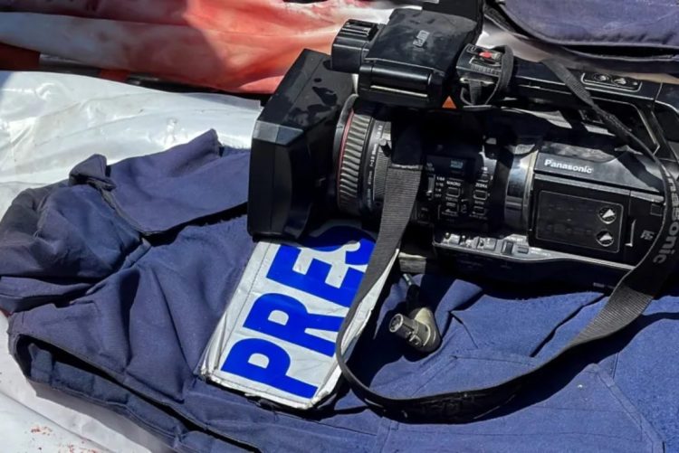 A Panasonic professional video camera rests on a blue press vest marked "PRES" during a media assignment. (Photo credit: Reuters)