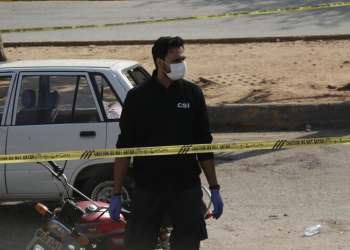 CSI investigator in protective gear examines the site of a suicide vehicle attack near a military checkpoint in South Waziristan, Pakistan. (Photo credit: Anadolu)