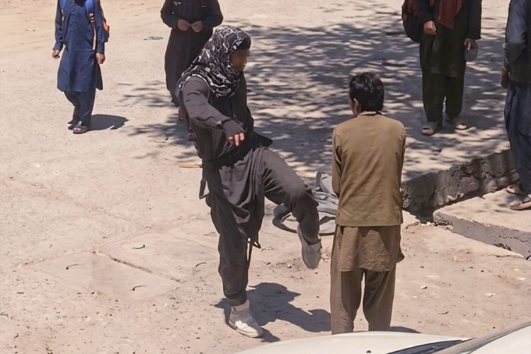 A Taliban fighter kicks a civilian in broad daylight on a Kabul street, as bystanders watch without intervening. (Photo credit: social media)
