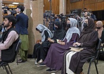 Female journalists wearing hijabs take notes during a press event surrounded by cameramen. (Photo credit: AFP)