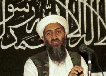 Osama bin Laden speaking in front of a black banner with Arabic calligraphy (Photo Credit: AP)