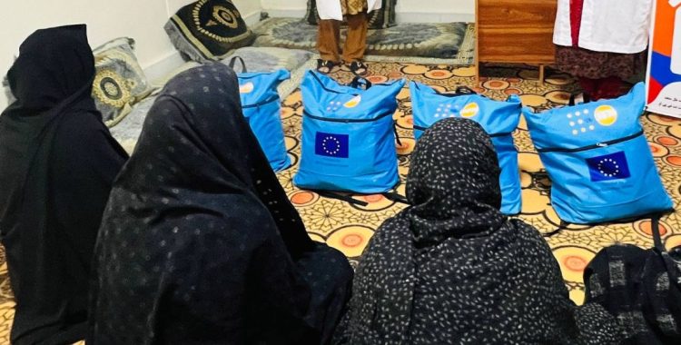Women sit before a row of EU-branded health kits distributed to support female returnees from Iran. (Photo credit: UNDP)
