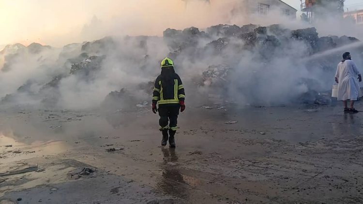 A firefighter and a civilian are seen at the scene of a major fire in Herat, as thick smoke rises into the sky. (Photo: MIAA)