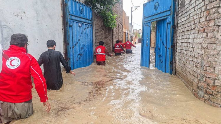 Red Crescent relief workers wade through floodwaters in a residential area to reach families displaced by recent flooding in Afghanistan. (Photo credit: @ECHO_Asia)