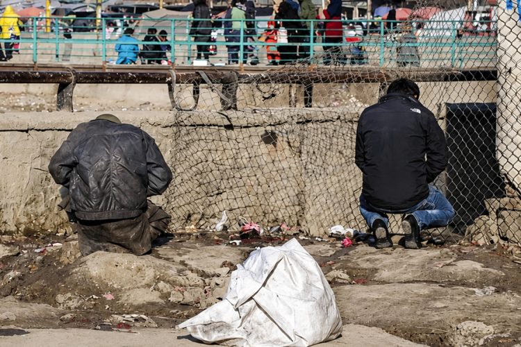 Two men relieve themselves against a roadside barrier in Kabul, illustrating the city's severe shortage of public toilets and its impact on residents' dignity and public health. (Photo credit: Social media)