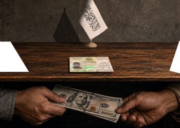 A tazkira sits on a desk beneath a Taliban flag as hands exchange US dollar bills, illustrating allegations of $500 bribes demanded for document verification at the Taliban's Emirate Affairs office in Kabul. (Photo credit: Exclusive / freepik)