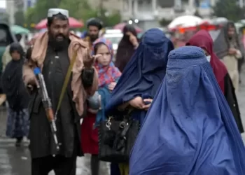 Afghan women in burqa as a Taliban soldier is seen in the background (Photo: AP)