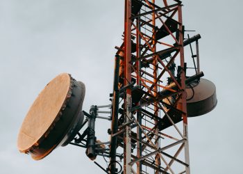 A telecom tower with satellite dishes stands against an overcast sky, reflecting infrastructure challenges facing mobile network users in Afghanistan. (Photo credit: Pexels)