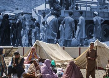 Displaced Afghan families rest beside tents at a refugee camp, as an overlaid image shows earlier scenes of migrants gathering near the border. (Photo credit: AFP)