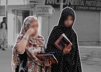 Two female students from Afghanistan carry textbooks while walking through a market street in Pakistan, where thousands face a stalled visa renewal process. (Photo credit: AFP)