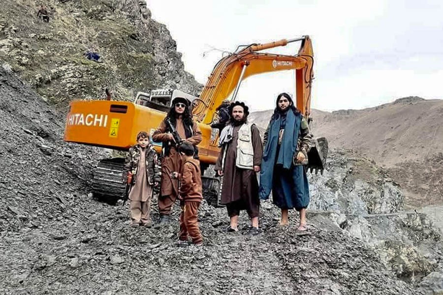 Armed men and children stand beside heavy excavation equipment at a mining site in northeastern Afghanistan. (Photo credit: Exclusive)