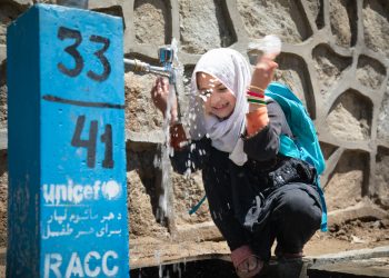 A young schoolgirl, dressed in her school uniform, uses clean water. She is happy to have access to safe drinking water. (Photo credit: UNICEFAfg/X@)
