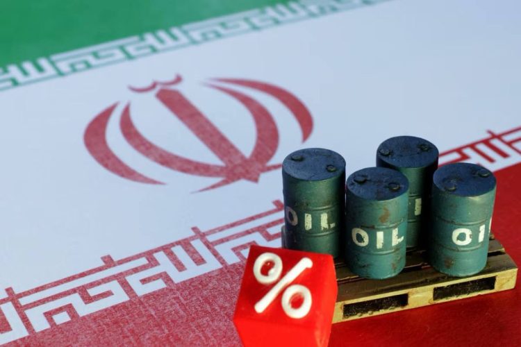 Miniature oil barrels are displayed in front of the Iranian flag, illustrating the decline in oil prices following the halt in reciprocal attacks between the United States and Iran. (Photo credit: Reuters)
