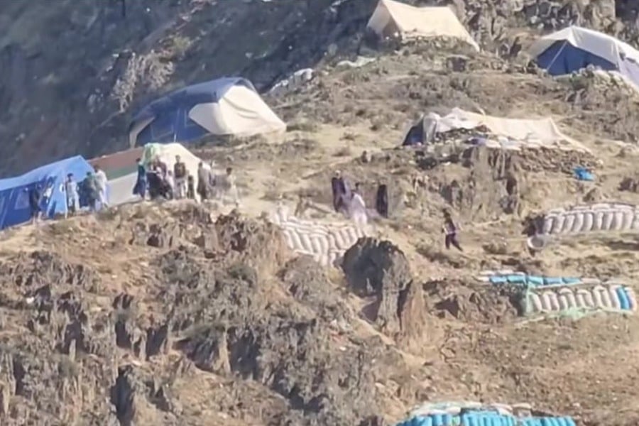 Tents and sandbag structures line a hillside mining camp in northeastern Afghanistan, where workers and armed personnel gather near excavation sites. (Photo credit: Exclusive)