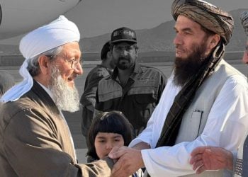A Mujaddadi family elder shakes hands with a senior Taliban official on an airport tarmac in Kabul. (Photo credit: Social Media)