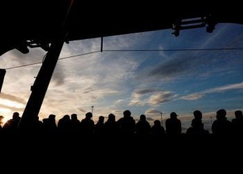 Silhouettes of people gather at a transit facility during sunset, illustrating the ongoing challenges faced by people of Afghanistan seeking asylum amid deportation concerns. (Photo credit: Reuters)