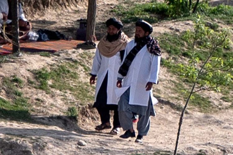 Two Taliban members walk through a rural area in Afghanistan amid reports of Morality Police pressure on residents. (Photo credit: AFP)