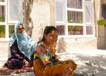 A young girl smiles while sitting with an elderly woman outside their home in Afghanistan (Photo: UN-Habitat)
