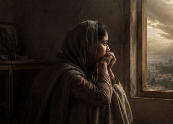 A young girl sitting in front of the window looking outside, lost in thought (Photo: AI)