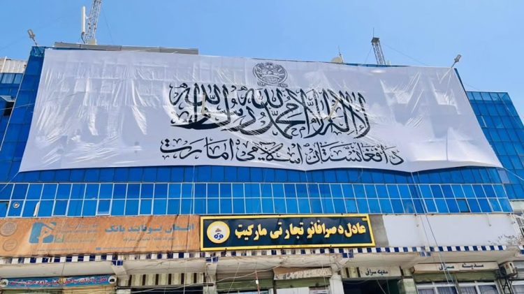 A large Taliban flag hangs over the front of a market in Mazar-e-Sharif. (Photo credit: Exclusive)