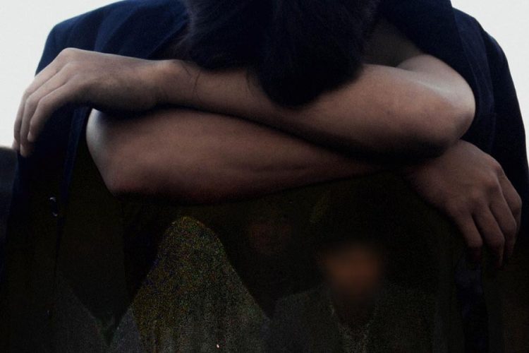 A person sits with arms crossed and head lowered, reflecting the emotional toll of delayed marriage amid economic hardship in Afghanistan. (Photo credit: Pexels + Social Media)