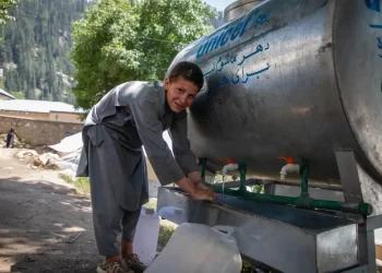 A boy collects water from a UNICEF water tank in Afghanistan following recent floods. (Photo credit: UNICEF)