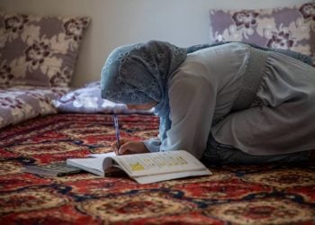 A girl studies from a textbook while seated on a traditional carpet at home in Afghanistan, as UNESCO reports nearly 70,000 people have benefited from its education programs. (Photo credit: UNICEF)
